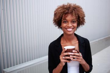 woman smiling while holding brown coffee mug in toronto