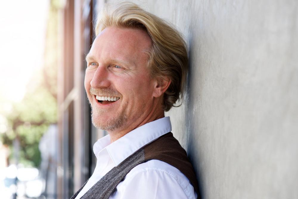 man smiling while leaning against wall