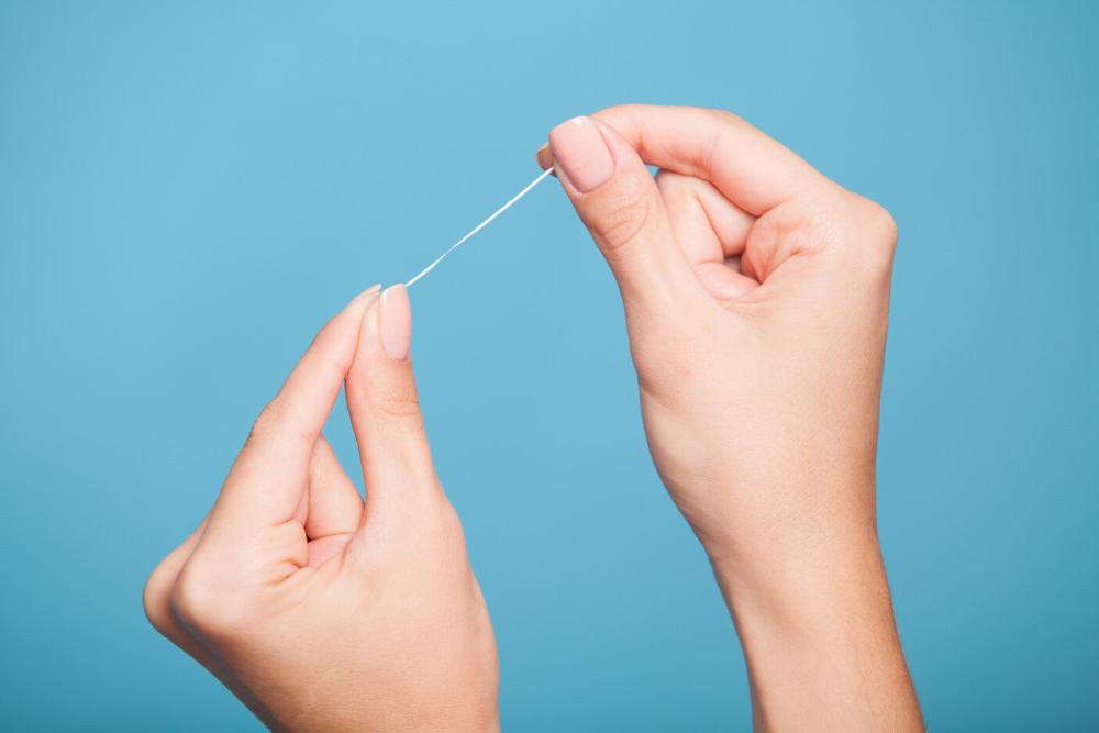 close up of hand holding dental floss