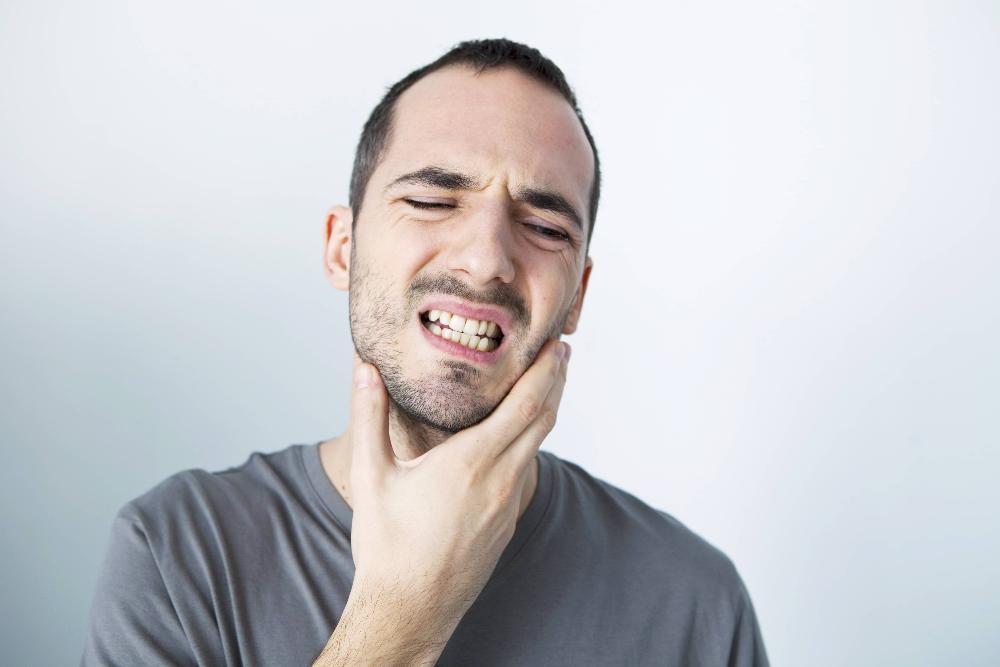 Man holding jaw from tooth pain before root canal in etobicoke