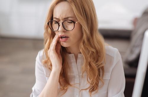 woman holding jaw from pain during emergency