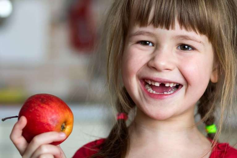 girl eating apple missing one front tooth