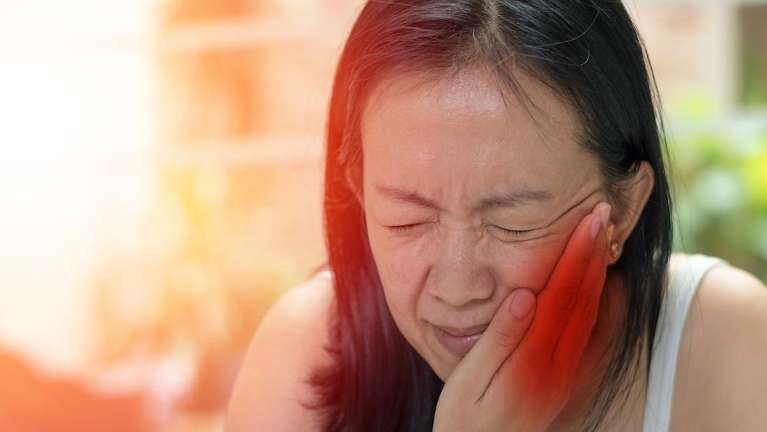 woman holding jaw from tooth pain during an emergency