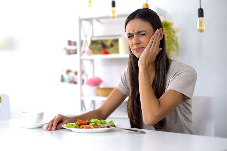 woman holding jaw from sensitive teeth