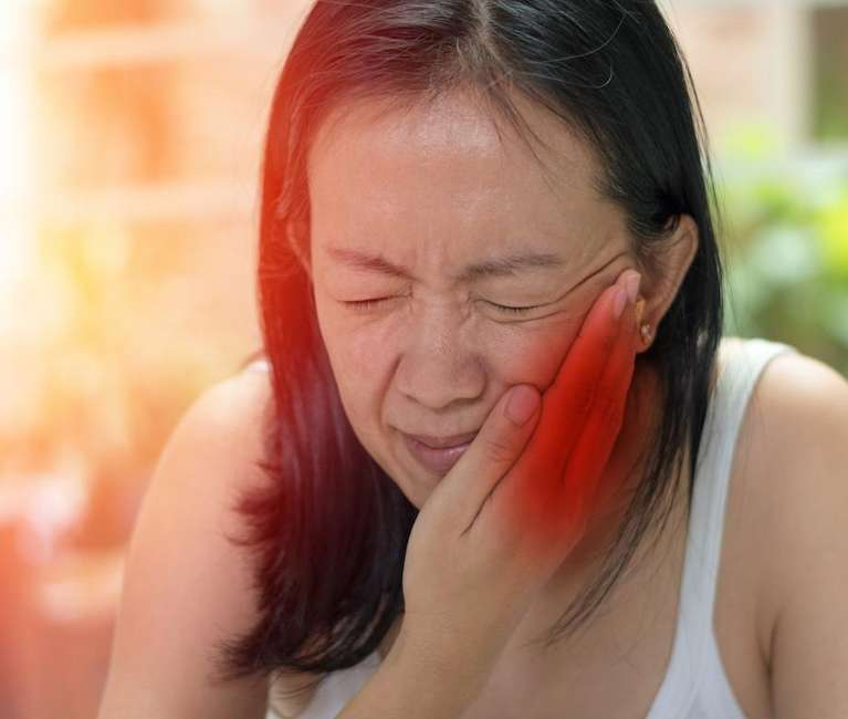 woman holding jaw from TMJ pain before botox treatment