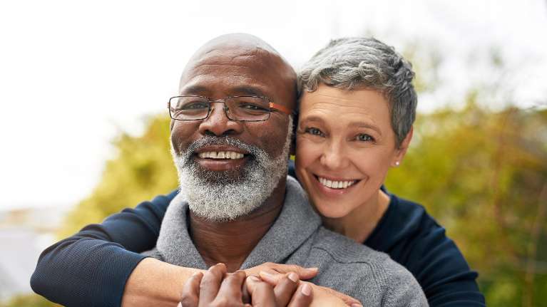 woman cuddling with husband, both smiling