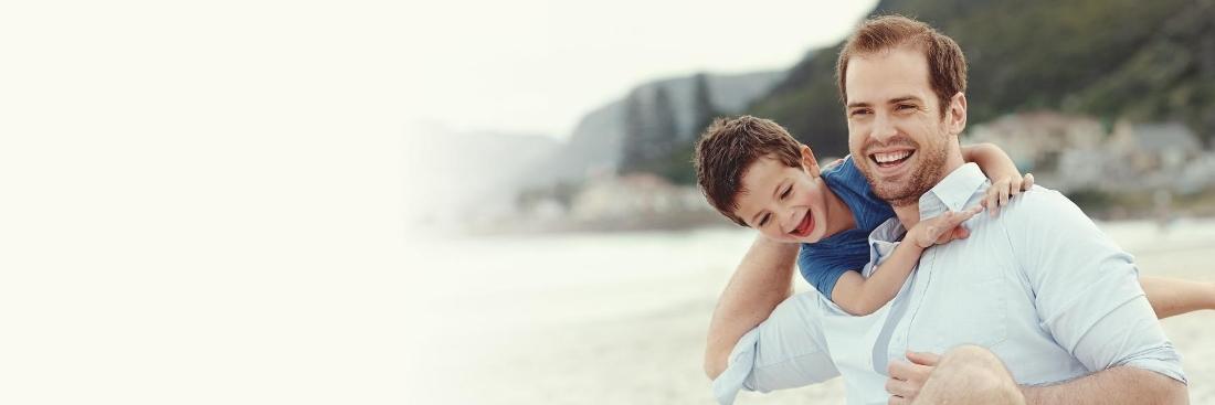 Father and son smiling on beach 