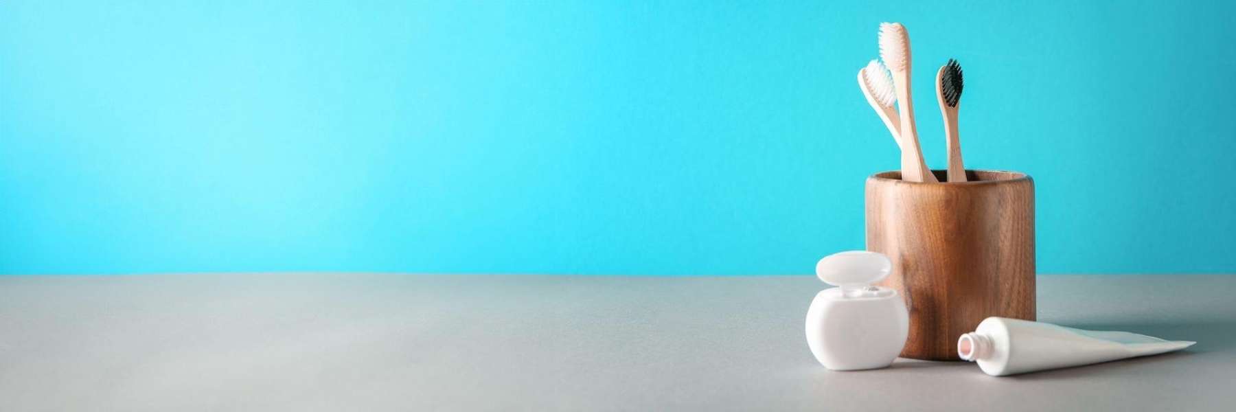 floss and toothpaste next to a cup filled with three toothbrushes