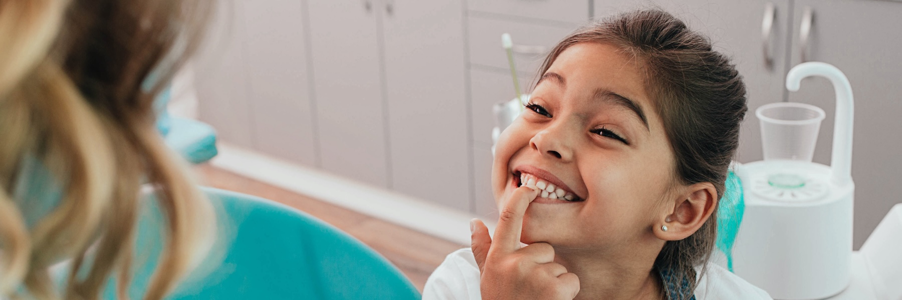 young girl showing her teeth to her dentist