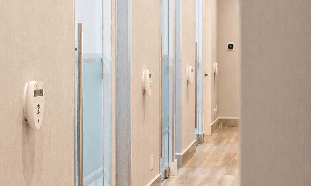 Modern dental office treatment hallway with glass-paneled operatory doors and hardwood floors